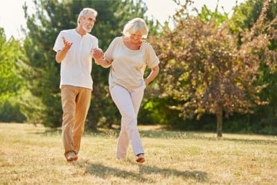 Couple walking hand-in-hand in a garden.