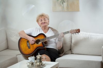 Senior resident playing guitar in a cozy living room