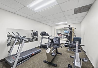 A gym area with exercise equipment in the facility