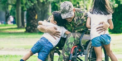 A soldier in a wheelchair playing with children in a park