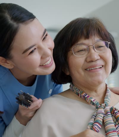 A caregiver smiling with a resident during a grooming session