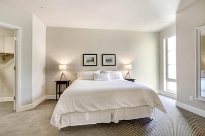 Well-lit, minimalist bedroom with bed and artwork.