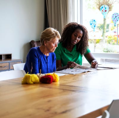 Two women engaged in a creative activity at a table.