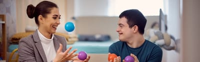 Staff member and resident enjoy playing with colorful balls.