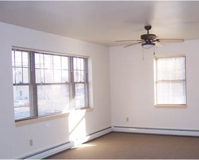 Empty room with windows and a ceiling fan.