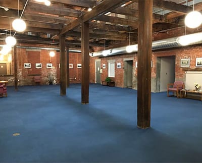 Spacious common area with exposed beams and blue carpet.