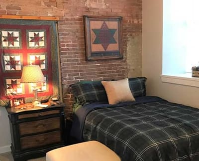 Cozy bedroom with quilt and brick wall