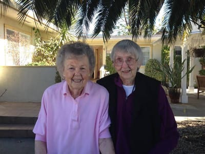 Two smiling residents in outdoor space