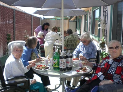 Seniors enjoying a meal outdoors at a table.