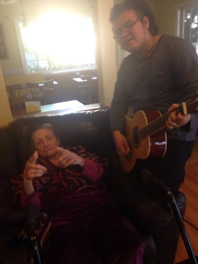 Resident interacting with a young musician indoors.