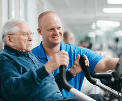 A staff member assisting a resident with exercise equipment