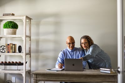 Two residents working together at a table with a laptop