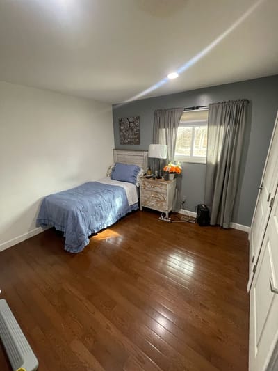 Cozy bedroom with blue bedding and wooden floor.