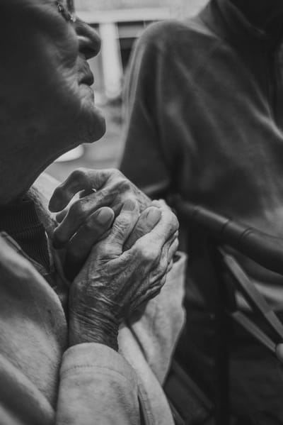 Elderly hands clasped together, gentle moment.