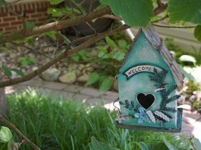 A decorative birdhouse hanging in a garden