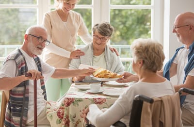 Residents enjoying food together in a sunny common area