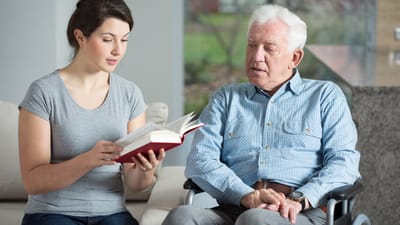 A caregiver reading to a resident in a comfortable setting