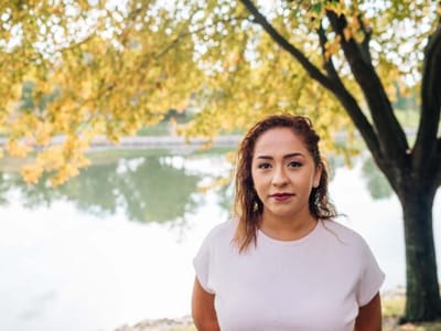 Young woman by a lake surrounded by trees