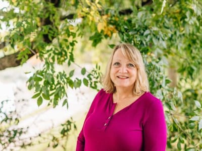 A resident smiling outdoors under a tree