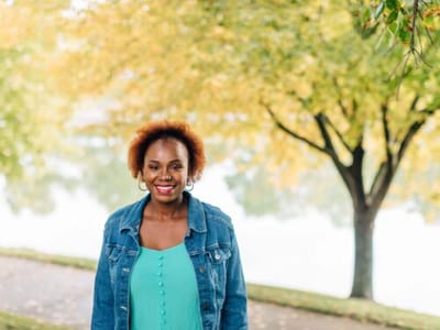 Smiling woman standing outdoors by a lake