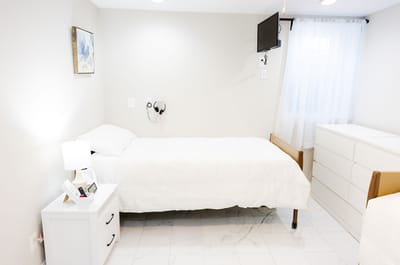 A private resident room with a bed and dresser