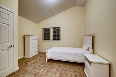 A simple, empty resident room with a bed and dresser