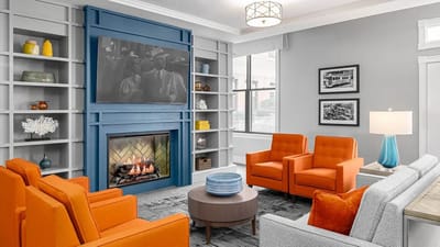 Cozy common area with orange chairs and fireplace