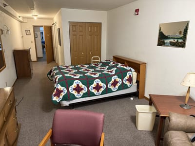 A private room with a bed, desk, and seating area