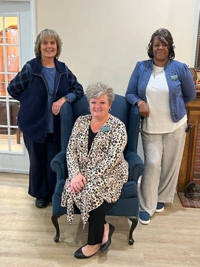 Three staff members posing together in a well-lit common area