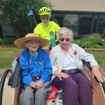Two residents smiling in an outdoor tricycle ride