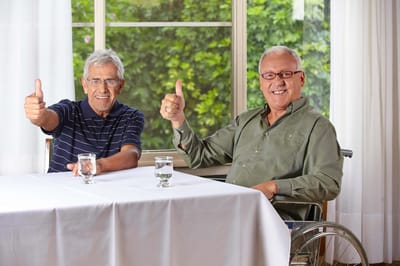 Two residents giving thumbs up while seated at a table