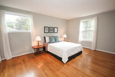 Bright, furnished bedroom with hardwood floor