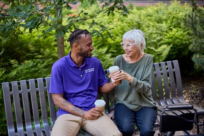 Resident and staff enjoying coffee in a garden