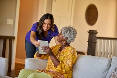 Caregiver showing a tablet to a resident in a common area