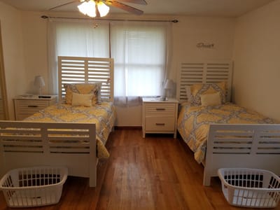 Shared bedroom with two beds and lamps.