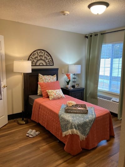 A nicely arranged private resident room with warm decor