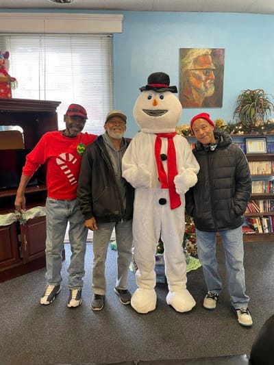 Residents posing with a snowman mascot at a holiday event