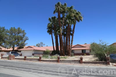Exterior view of a senior living home with palm trees