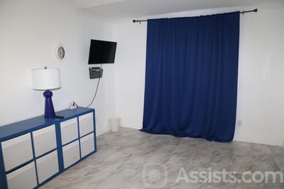 We Care Residential Home, assisted living in Las Vegas, NV — Empty room with blue curtains and minimalist furniture