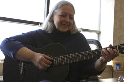 A resident playing guitar with a smile in their room