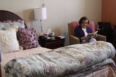 A resident reading a book in her private room