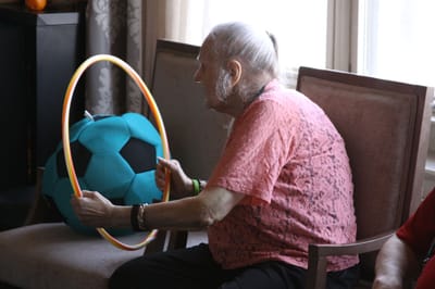 An elderly resident participating in a hula hoop activity