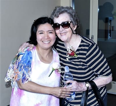 Two residents smiling together in a bright facility hallway