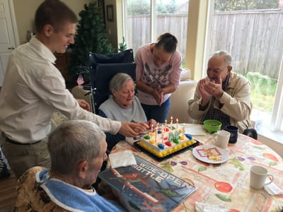 Residents celebrating a birthday with a cake.
