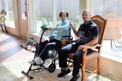 Resident exercising with staff member in a sunny room