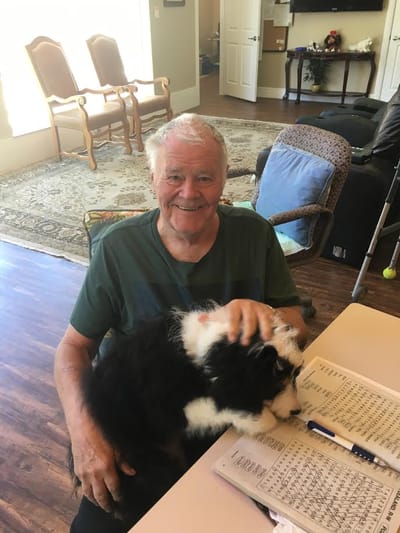 Senior man smiling with a puppy in a common area