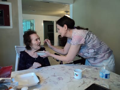 A caregiver feeding a resident at a table