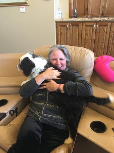 Resident joyfully holding a dog in the lounge area