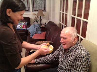 Caregiver feeding an elderly resident in a cozy living room