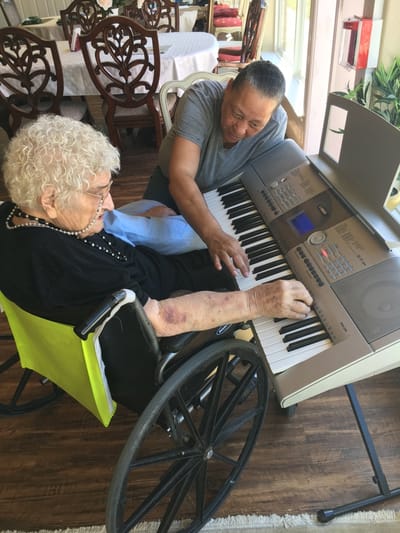 Resident and staff member playing piano together